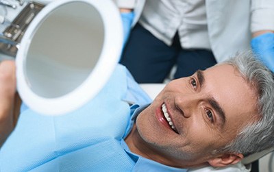 a patient checking his teeth with a mirror