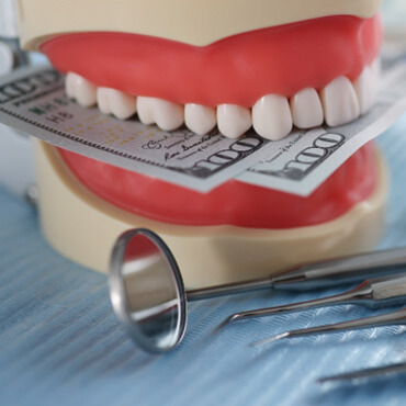 mouth mold holding money next to dental instruments