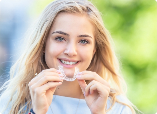 woman holding invisalign and smiling