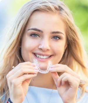 woman holding invisalign and smiling